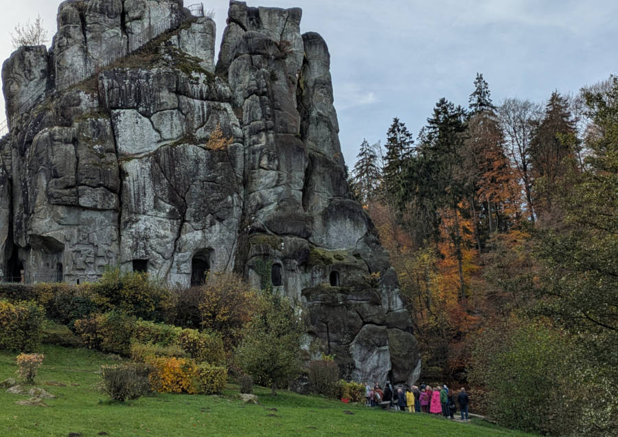 Bei herbstlicher Stimmung betrachtet eine Besuchergruppe das offene Felsengrab an den Externsteinen Foto:LVL