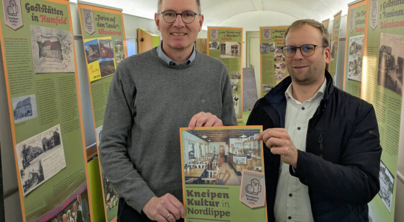 Borris Ortmeier, Bürgermeister der Stadt Barntrup und Vorsitzender der Lokalen Aktionsgruppe (LAG) Nordlippe (r.), freut sich zusammen mit Jochen Brunsiek, Geschäftsführer des Kulturstellwerks Nordlippe über die 15-teilige Wanderausstellung zur Kneipenkultur in Nordlippe. Zur Präsentation war die Ausstellung im Europawaggon am Bahnhof Farmbeck zu sehen. Nun wandert sie durch die Region.. Foto: Kulturstellwerk Nordlippe