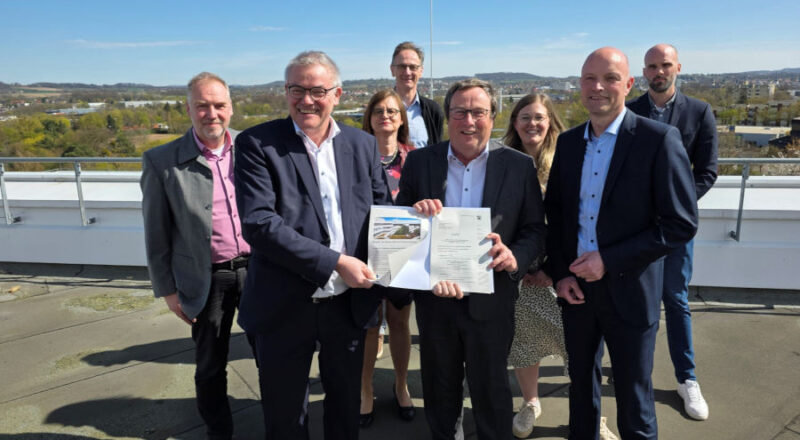 Umweltminister Oliver Krischer (Mitte) und Jens Kronsbein, Leiter der Abteilung Regionale Entwicklung bei der BezReg (rechts), überreichen Rainer Grabbe (links) und dem Projektteam beim Kreis Lippe den Förderbescheid für die Umsetzung der klimaangepassten Außenanlagen am Kreishaus. Foto: Kreis Lippe