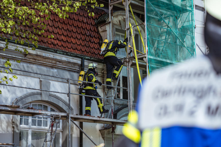 Zwei Kräfte der Freiwilligen Feuerwehr Leopoldshöhe ersteigen unter Atemschutz das Gerüst an dem Gebäude. Foto: Die Blaulichtfotografen