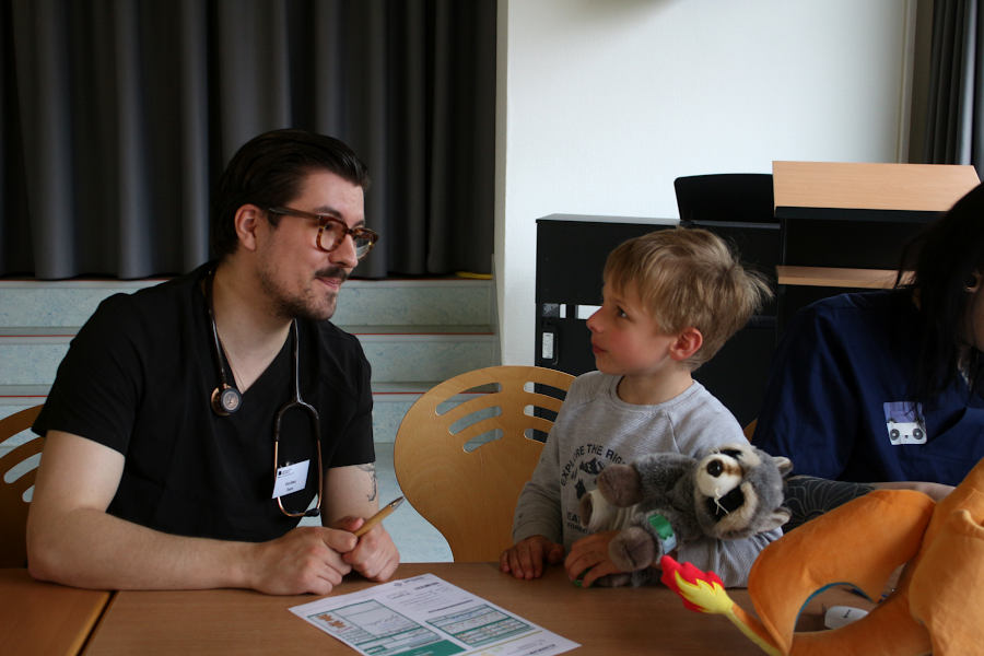 Medizinstudent Tom Gerber, Arzt im Teddybärenkrankenhaus im ernsten Anamnesegespräch mit Nick-Linus Radmer und seinem Waschbären. Foto: Edeltraud Dombert