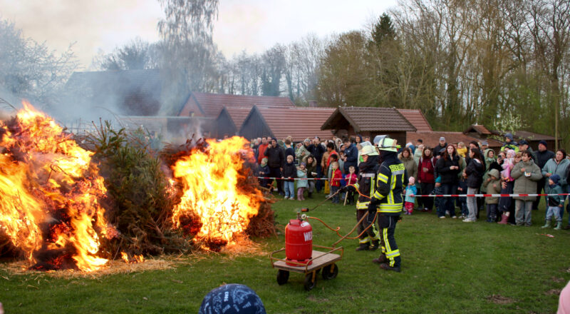 Zwei Feuerwehrleute fachten das Osterfeuer des Heimatvereins auf dem Heimathof an. Foto: Thomas Dohna