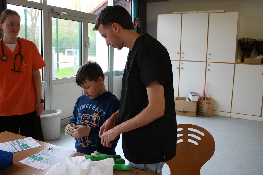 Medizinstudent Nico Sentker, Arzt im Teddybärenkrankenhaus (rechts) erklärt Jason Brüning, wie er sein Kuscheltier richtig mit einem Heftpflaster versorgt. Foto: Edeltraud Dombert