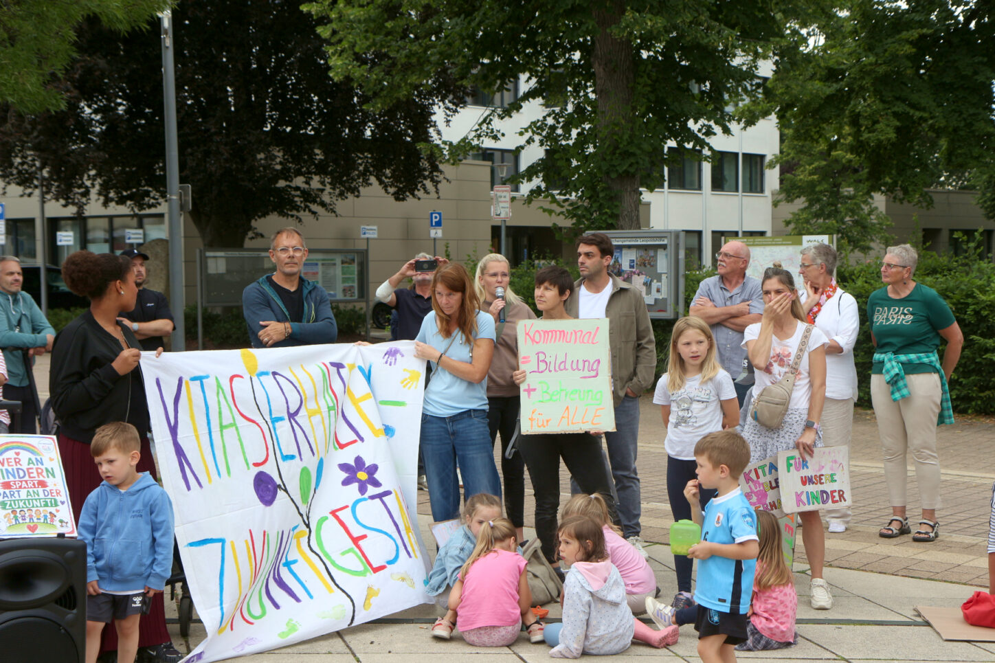 Mareike Loges (mit Mikrophon), Sprecherin der Initiative zum Erhalt der kommunalen Kitas, spricht zu den Demonstrierenden. Foto: Thomas Dohna