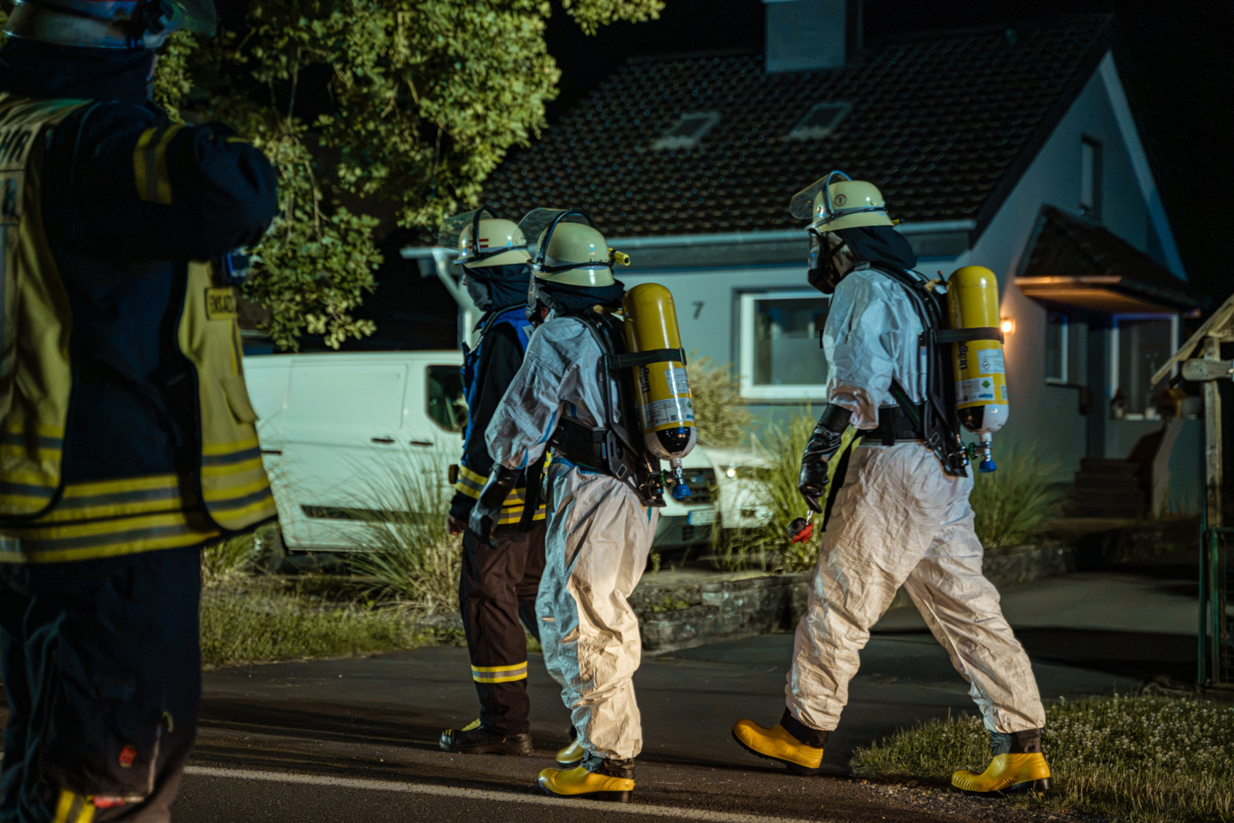 Einsatzkräfte der Feuerwehr in sogenannten Einmalanzügen gehen unter Atemschutz zu ihrem Einsatz. Foto: Die Blaulichtfotografen