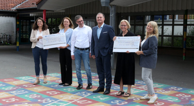 Sandra Fahrenkamp (links) und Isabel Loh (rechts) übergeben die symbolischen Schecks an die Leiterinnen der Grundschule Asemissen Diana Fleer (zweite von links) und der Grundschule Nord Madlen Klarhorst (zweite von rechts). Mit den Schulen freuen sich Bürgermeister Martin Hoffmann (dritter von links) und der Vorstandsvorsitzende der Volksbank Matthia Kruse (dritter von rechts). Foto: Edeltraud Dombert