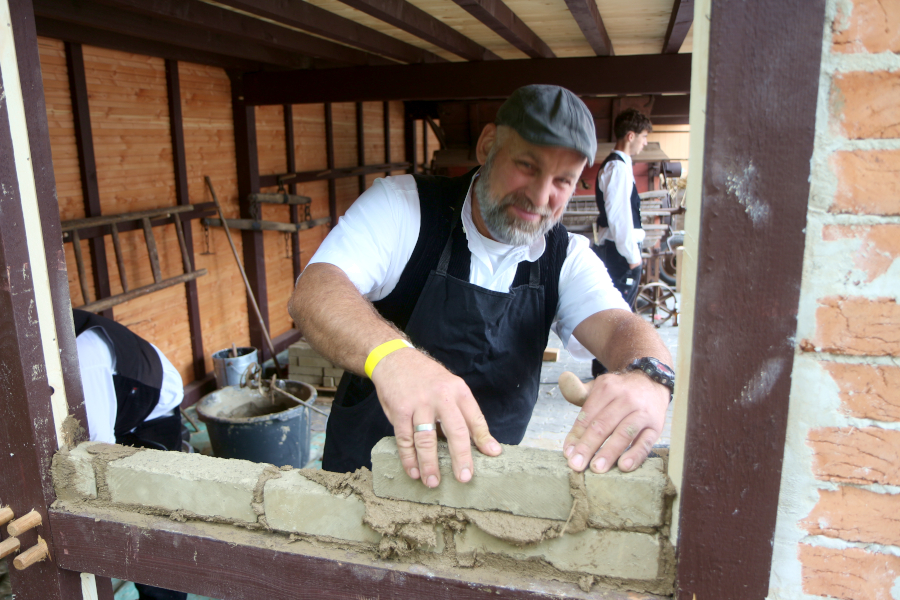 Benjamin Neunes zeigt an der neuen Remise, wie man mit Lehmziegeln und Lehm mauert. Foto: Thomas Dohna