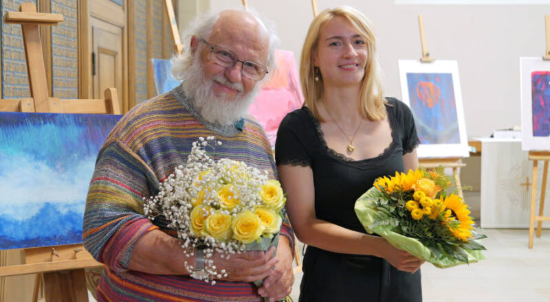Kantorin Leonie Deutschmann und Künstler Wolfgang H. Schmutz inmitten seiner Bilder. Foto: Lippische Landeskirche