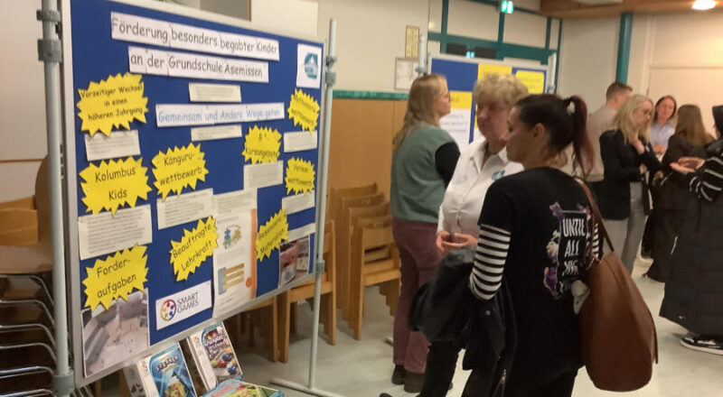 Lehrerin Birgit Nabben (zweite von rechts) erklärt einer Interessentin anhand der Schautafel die Begabtenförderung an der Grundschule Asemissen. Foto: GS Asemissen