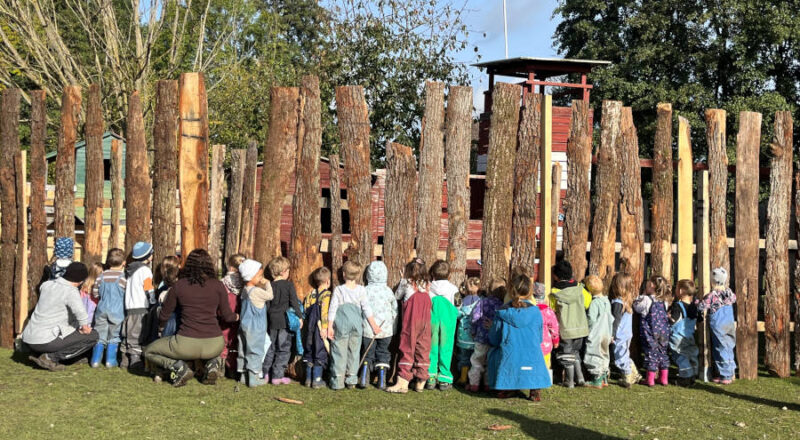 Neigierig luken die Kinder des Kita Greste durch den Holzzaun auf dem Kastanienhof. Foto: Privat