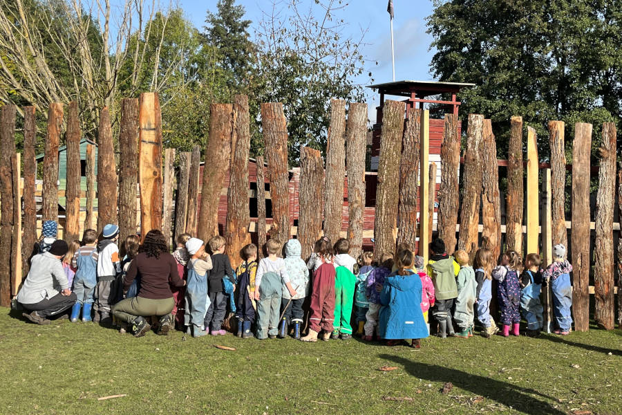 Neigierig luken die Kinder des Kita Greste durch den Holzzaun auf dem Kastanienhof. Foto: Privat